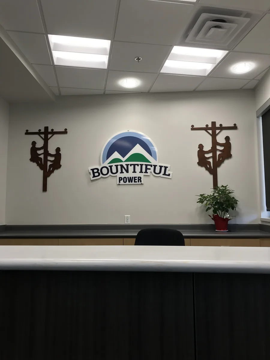 Bountiful Power lobby with custom metal-cut lineman silhouettes flanking the company logo