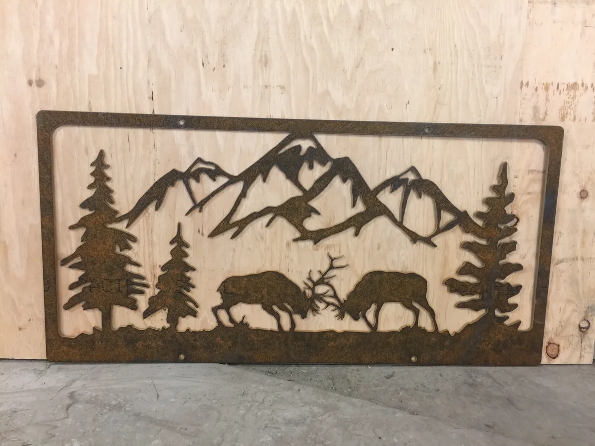 Waterjet-cut metal wall panel depicting sparring elk in a mountain and pine scene