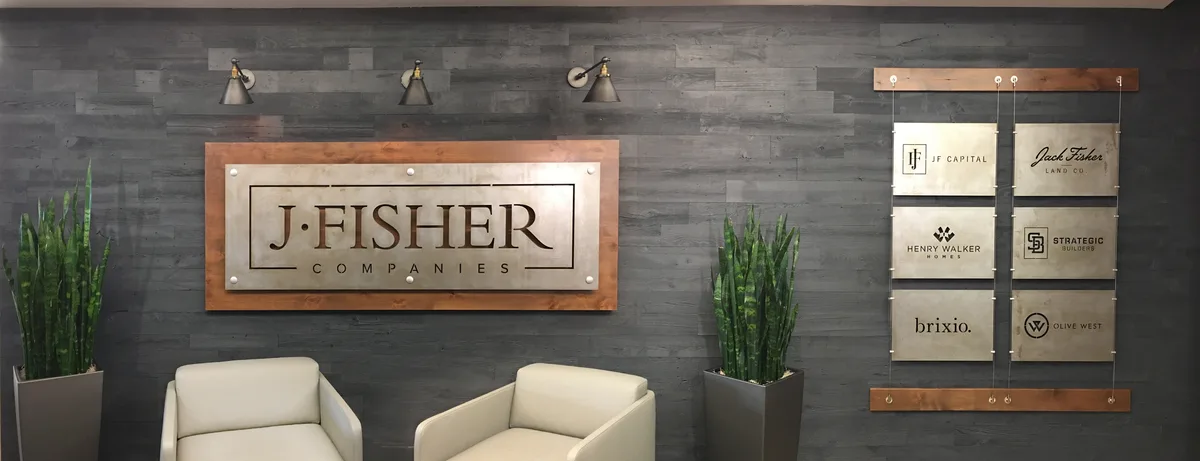 Custom metal lobby sign fabricated for J. Fisher Companies, installed on a wood-paneled wall