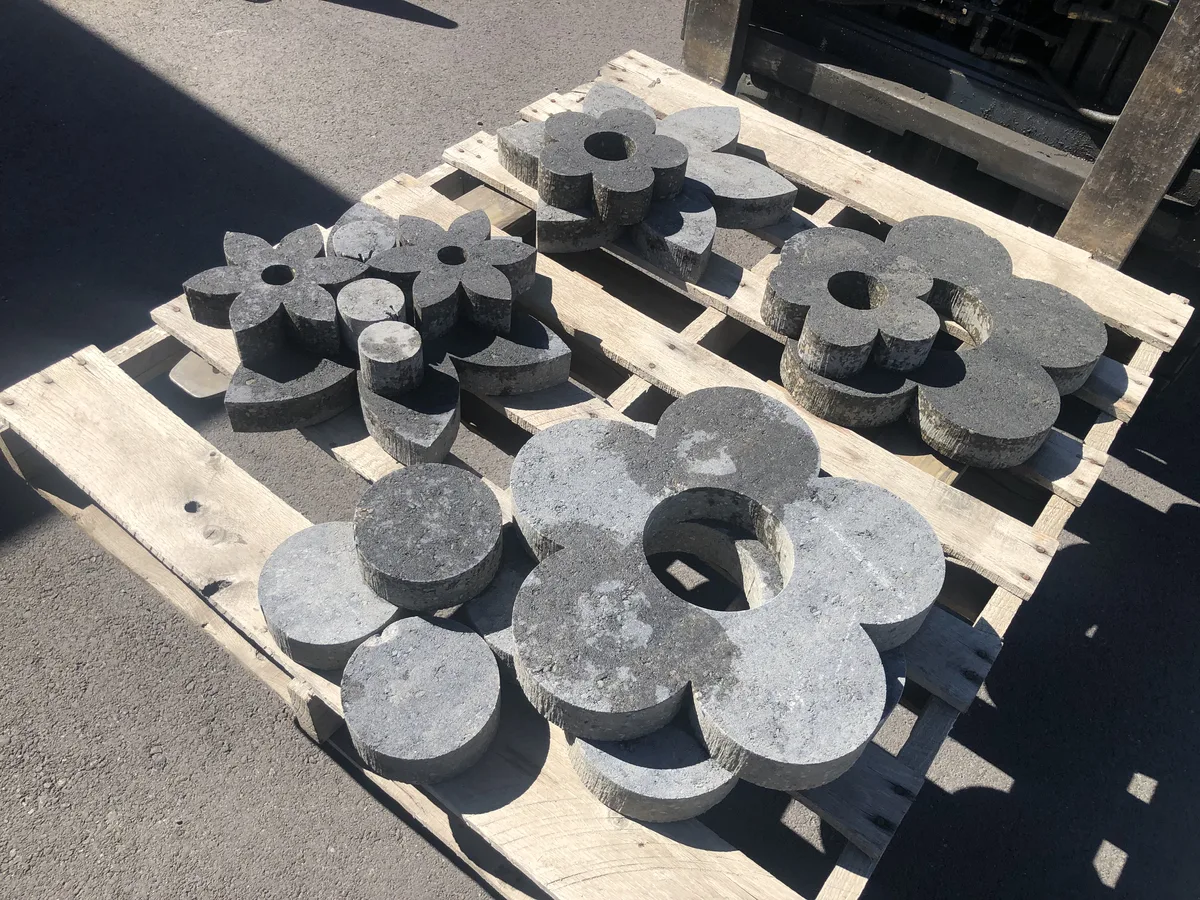 Waterjet-cut stone flower and disc shapes stacked on a pallet, showing stone-cutting capability